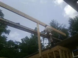 Carpenter setting a ridge beam over a new addition frame — Ice Dam Removal by Roofing Brothers in Loreauville