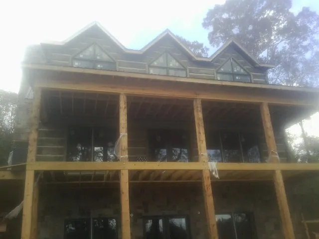 Dormers and porch framing on a large log home under construction — Roof Coating work by our crew in Loreauville