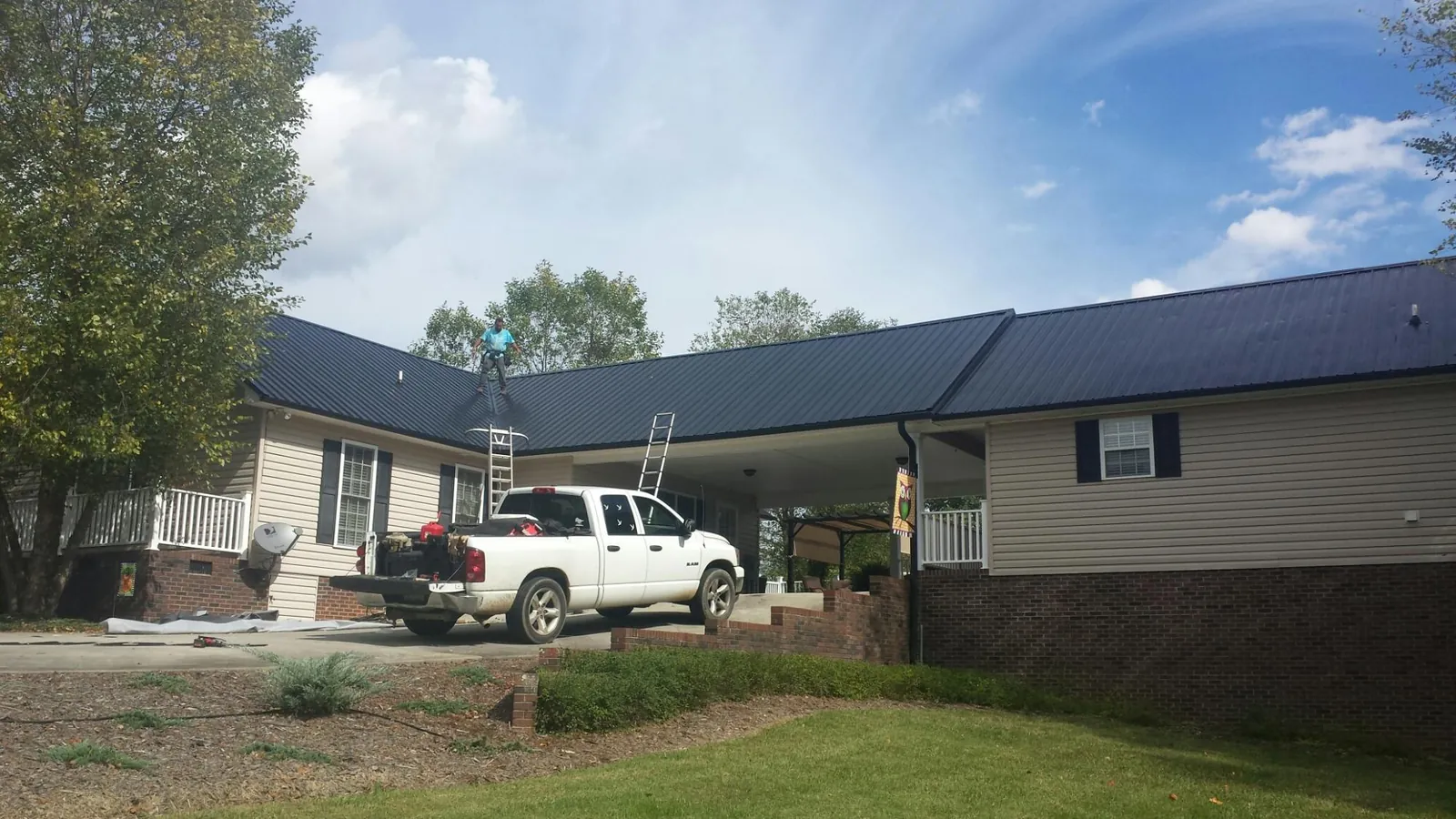 Black metal roof over a home and attached breezeway with ladders set in Loreauville