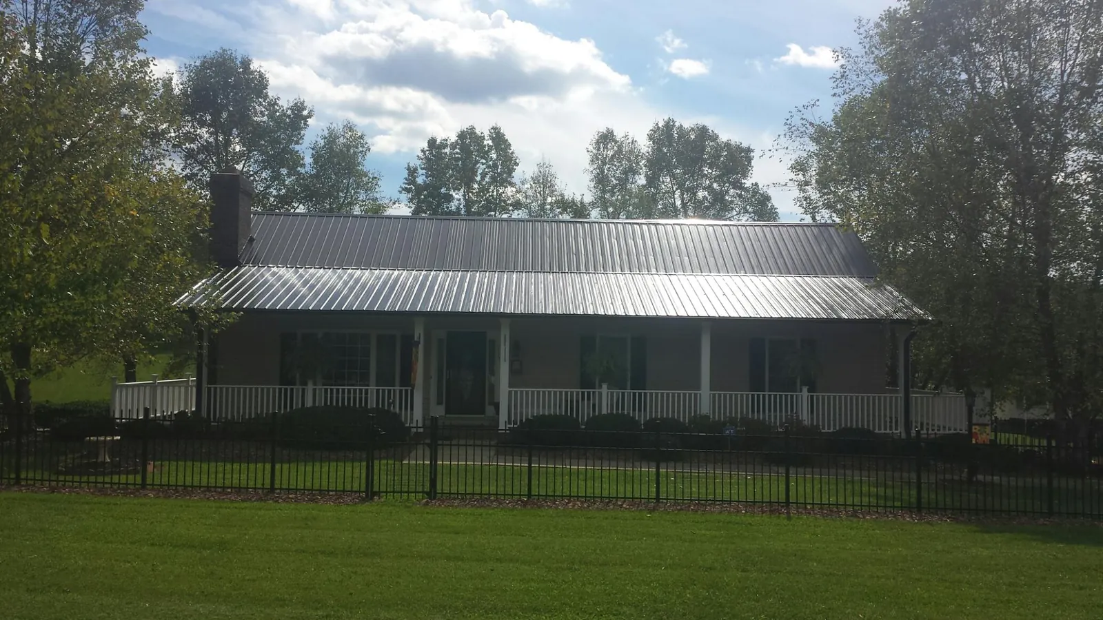 Gray metal roof on a brick ranch with a full width front porch — Gutter Guard Installation work by our crew in Loreauville